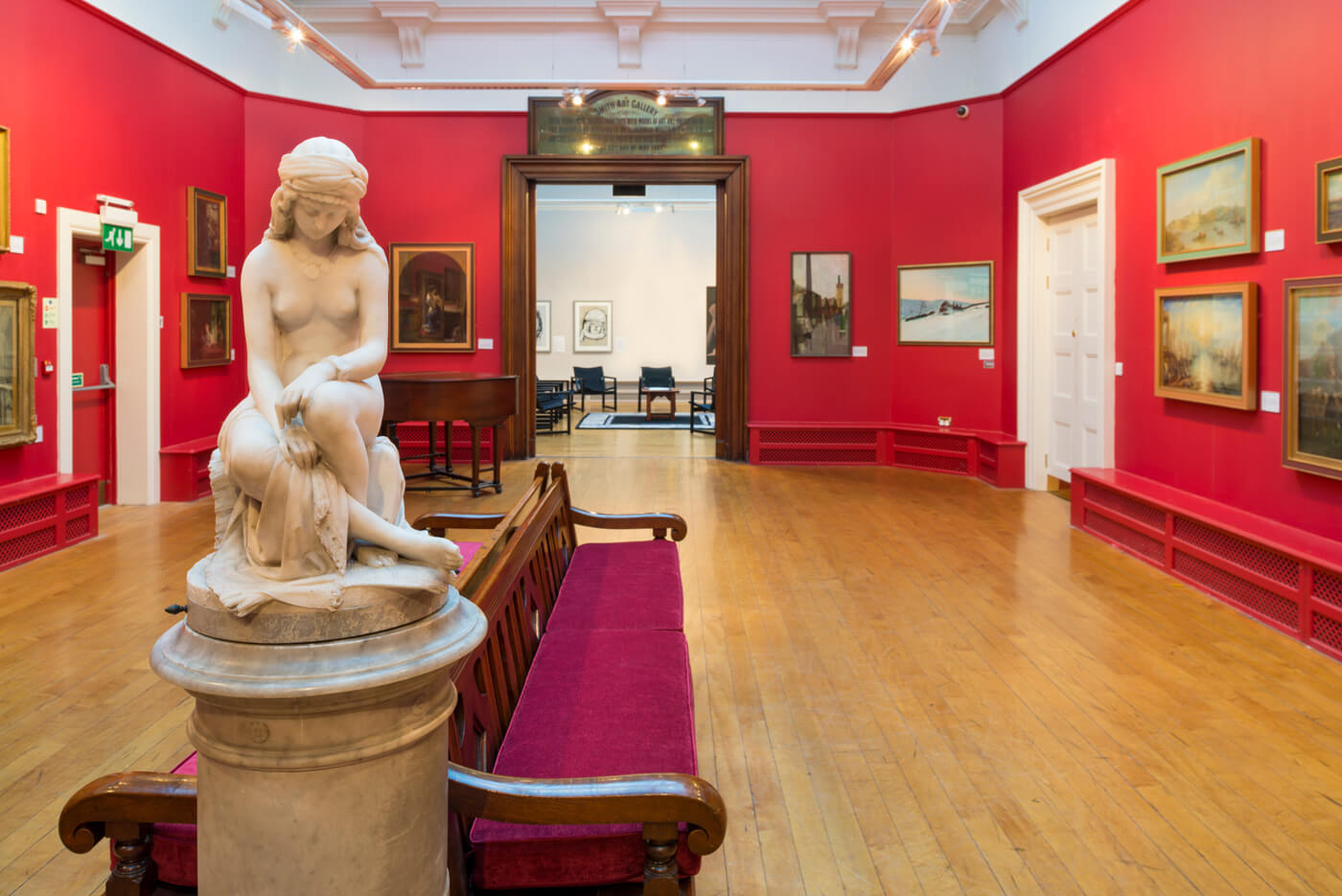 A prominent statue of a lady in a room with walls of framed art